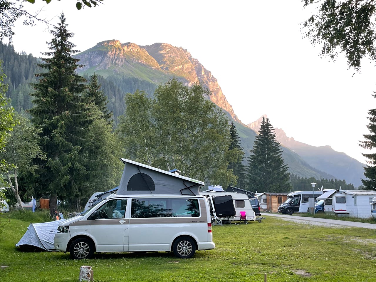 A van parked in front of a campground with mountains in the background